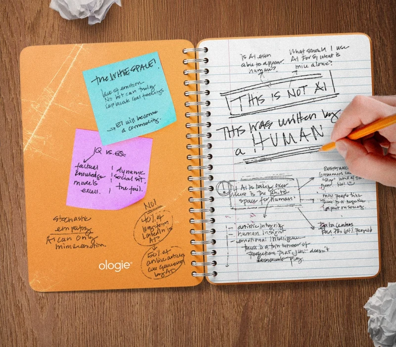 An open spiral notebook filled with handwritten notes about AI and emotional intelligence, including the phrase “This is not AI. This was written by a human.”